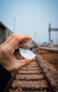 Midsection of person holding glass against clear sky