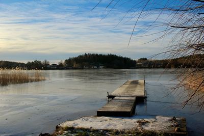 Pier on lake against sky during winter