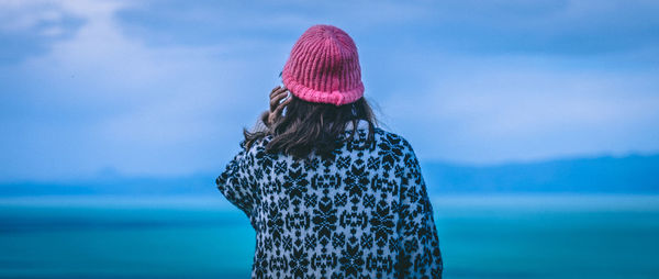 Rear view of woman standing by sea against sky