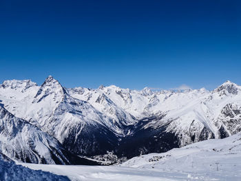 Scenic view of snowcapped mountains against clear blue sky