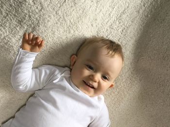 High angle view of smiling toddler lying on bed at home