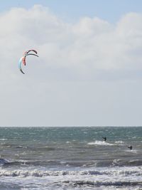 Person paragliding on beach against sky