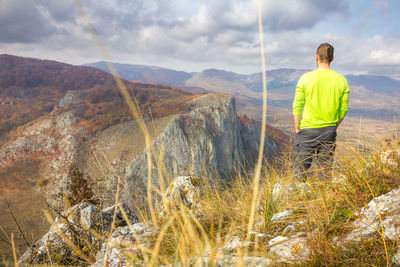 Rear view of man standing on mountain against sky