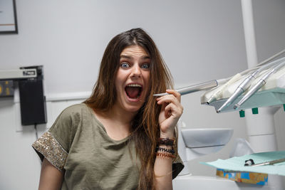 Portrait of young woman sitting in the chair of a dental clinic making faces