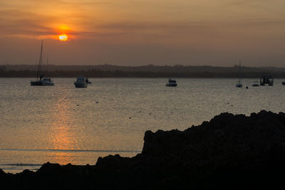 Silhouette of boats in sea during sunset