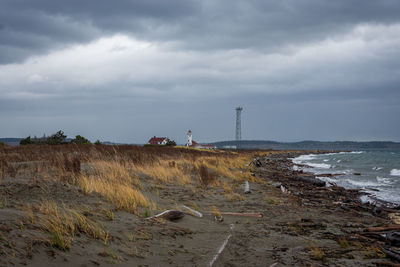 Scenic view of beach against cloudy sky