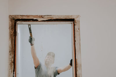 A man working with a crowbar in a doorway.