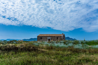 Abandoned building on field against sky