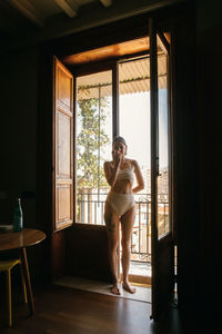 Woman standing by window at home