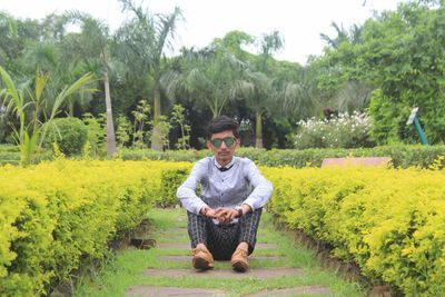 Full length portrait of young man sitting on land