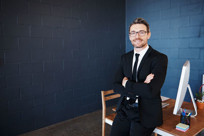 Portrait of a smiling young man sitting against wall