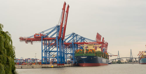 Cranes at pier against sky