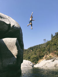 Low angle view of carefree shirtless boy jumping in yuba river from cliff