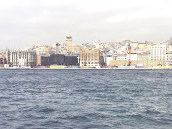 Sea by cityscape against sky