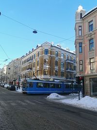 View of city street and buildings against blue sky