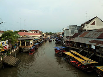 Boats in canal amidst buildings in city against sky
