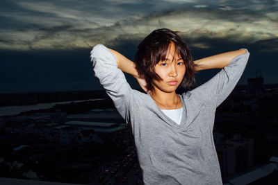 Portrait of young woman standing against sky during sunset