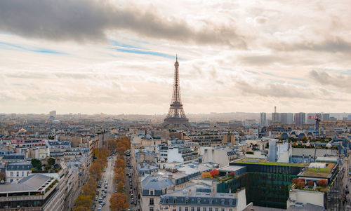 Aerial view of buildings in city against cloudy sky