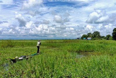 Man working on field against cloudy sky