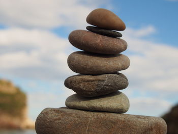 Close-up of stone stack on rock against sky