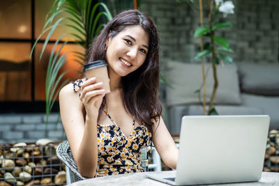 Portrait of young woman using laptop at cafe