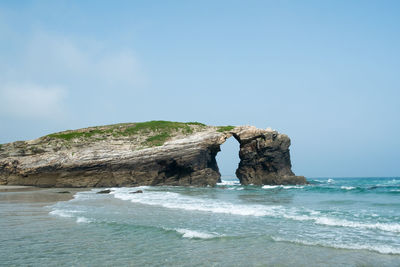 Rock formation in sea against sky