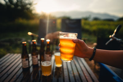 Cropped hand of woman holding beer glass on table