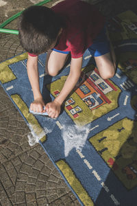 High angle view of boy cleaning carpet outdoors