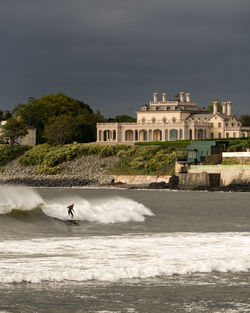 During a hurricane, a man catches a wave surfing in front of a mansion in newport, rhode island.