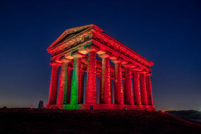 Low angle view of illuminated building against sky at night