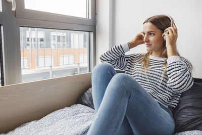 Young woman using mobile phone while sitting on sofa at home