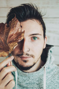 Close-up portrait of man holding maple leaf