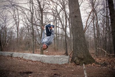 Young man backflipping on field at forest