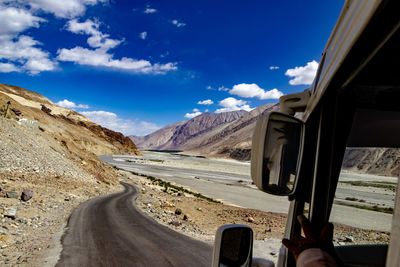 Road by mountains against sky