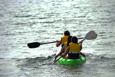 Rear view of people enjoying in sea