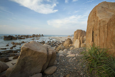 Rock formations on beach against sky