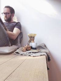 Mid adult man reading newspaper while sitting by breakfast against wall