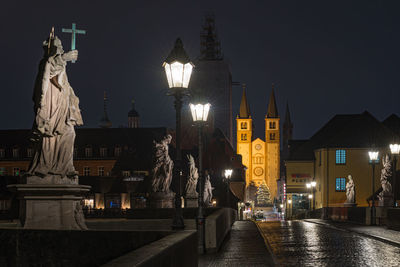 Illuminated city street and buildings against sky at night