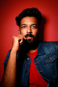 Portrait of young man smoking cigarette against yellow background