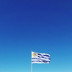 Low angle view of flag waving against blue sky