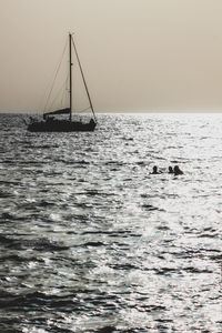 Silhouette sailboat sailing on sea against sky