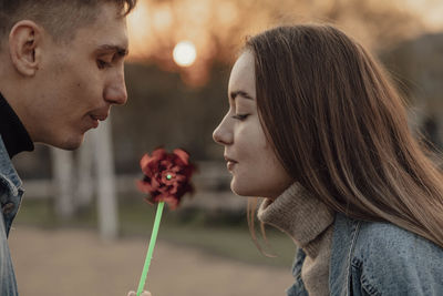 Young man and woman blowing on a wind toy, ecology concept