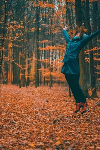 Full length of man with autumn leaves in forest