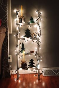 Illuminated lamp on table against wall at home