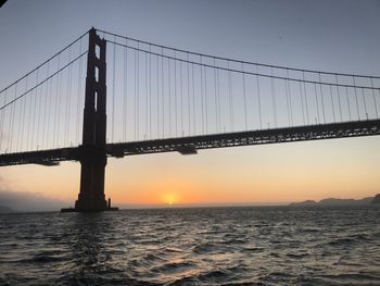 View of suspension bridge over sea during sunset