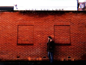 Full length of man standing against brick wall