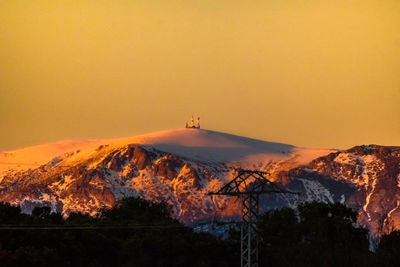 Scenic view of snowcapped mountains against orange sky