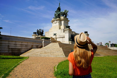 Back view of beautiful young tourist woman visiting the monument to the independence of brazil.