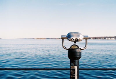 Close-up of coin-operated binoculars against sea