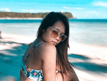 Portrait of young woman in bikini standing at beach